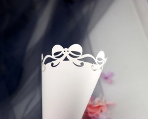Close-up of laser-cut white paper cone with delicate lace bow design for wedding confetti