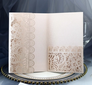 Detail of champagne laser-cut lace wedding invitation pocket on elegant display plate