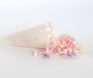Detail of cream lace cone with heart cutouts filled with mixed dried flower petals