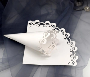 Detailed laser-cut white lace paper cone with bow design for wedding petal confetti