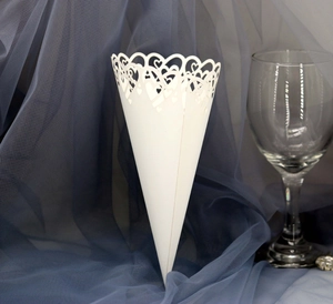 Close-up of laser-cut heart patterns on white wedding confetti cones in a romantic setting