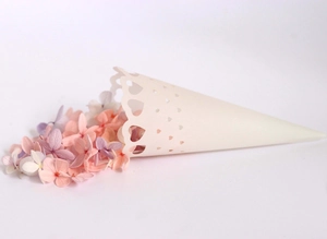 Close-up of laser-cut white heart confetti cone with hollow patterns for wedding petals
