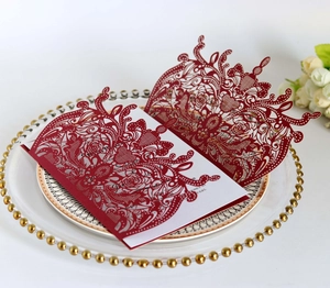 Laser cut burgundy wedding invitation with hollow floral pattern on a decorative gold plate