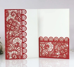 Detail of red laser-cut wedding invitation with lace pattern and glitter finish