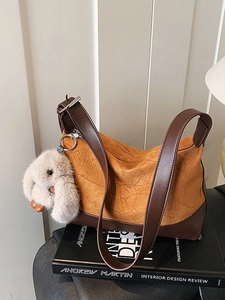 Ruched ginger and brown crossbody bag with rabbit charm on a stylish art book