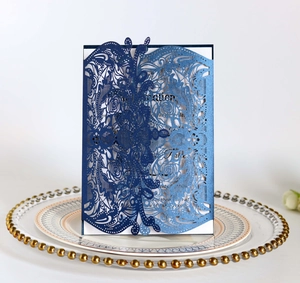 Detail of laser-cut navy blue floral wedding invitation on gold rimmed glass plate