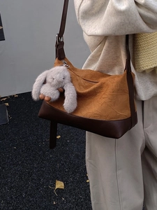 Pleated ginger yellow crossbody bag with brown straps and cute rabbit charm on a model