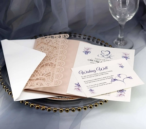 Detailed laser-cut pocket wedding invitation set with floral cards on a glass tray