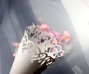 Macro view of laser-cut heart patterns on white paper wedding confetti cones