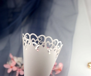 Close-up of white paper wedding confetti cone with laser-cut heart hollow lace design