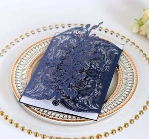 Detail of dark blue laser-cut rose floral invitation on decorative gold glass tray