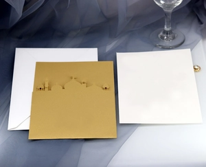 Détail de carte d'invitation dorée découpée au laser avec silhouette de mosquée et enveloppe