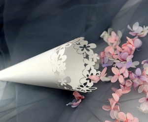 Close-up of laser-cut white wedding petal cones with intricate floral lace patterns