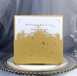 Elegant gold laser-cut wedding invitation with star and moon patterns on a dinner plate
