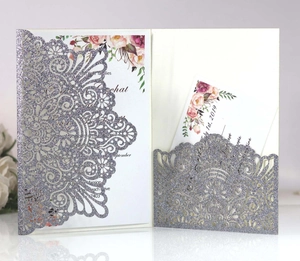 Macro view of laser-cut silver glitter wedding invitation with floral insert card
