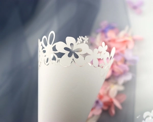 Macro shot of white laser-cut floral hollow pattern on wedding confetti paper cone