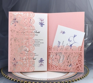 Close-up of pink laser cut wedding invitation set with intricate lace floral envelope design