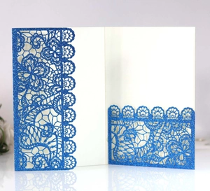 Close-up of royal blue laser-cut glitter wedding invitation with floral lace pattern