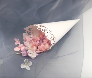 Close-up of laser-cut white wedding petal cones filled with colorful dried flowers
