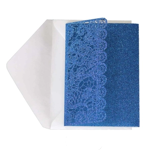 Macro view of blue glitter laser-cut lace wedding invitation with white envelope