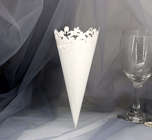 Detail of laser-cut hollow floral lace on white paper wedding confetti cone for ceremony