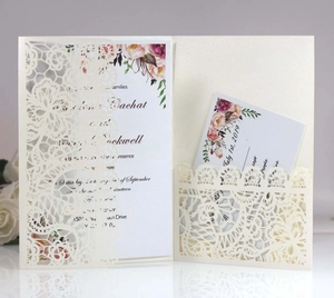 Detailed laser-cut lace wedding invitation with elegant floral insert cards on a stand