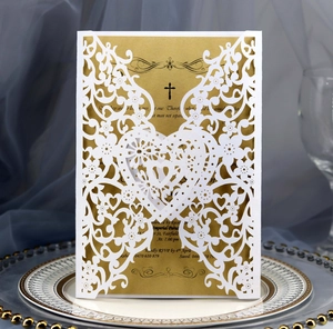 Detailed laser-cut white heart wedding invitation with gold cardstock on blue fabric