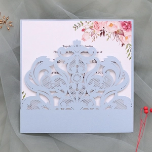 Macro detail of laser-cut lace wedding invitation with light blue glitter floral cover