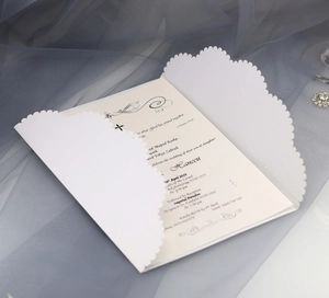 Faire-part de mariage blanc découpé au laser avec bords ondulés sur fond en tulle bleu