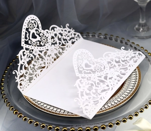 Detail of white laser-cut heart and floral lace design on premium wedding invitation