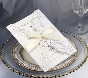Macro detail of laser-cut rose hollow invitation with elegant cream ribbon and inner card