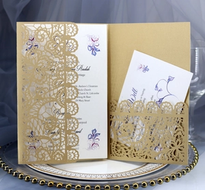 Macro shot of gold laser-cut floral wedding invitation with RSVP card on silk fabric