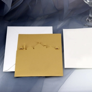 Élégante carte de vœux découpée au laser dorée et enveloppe sur fond de tissu bleu