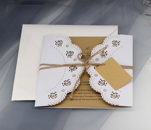 Macro detail of laser cut rose pattern on white invitation with kraft paper and jute twine
