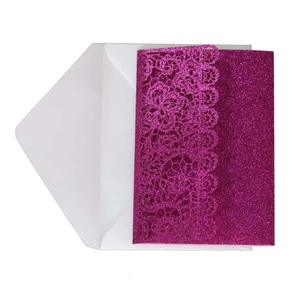 Macro shot of laser-cut fuchsia glitter wedding invitation with delicate floral lace patterns