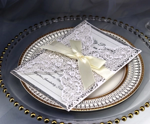 Close-up of laser-cut floral pattern with silk ribbon on pink wedding invitation card