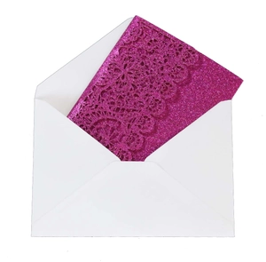 Detail of rose pink glitter laser-cut invitation card with floral lace pattern and white envelope