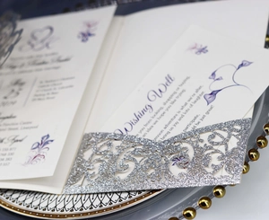 Close-up of silver glitter laser-cut wedding invitation with elegant floral detail