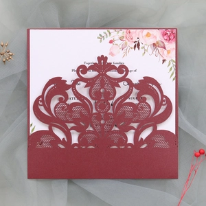 Close-up of burgundy laser-cut lace wedding invitation with floral insert card