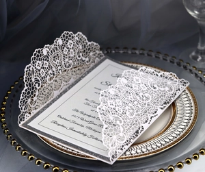 Detail of laser-cut lace invitation with silver glitter insert on a decorative plate