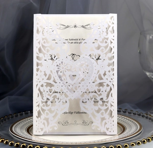 Detail showing white laser-cut heart and floral textures on wedding invitation cards