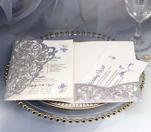 Detail of silver glitter laser-cut wedding invitation with floral lace pattern and inner cards