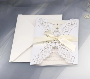 Detail of laser-cut rose wedding invitation with cream ribbon and elegant envelope