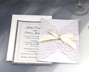 Detail of laser cut wedding invitation with white silk bow and elegant calligraphy font