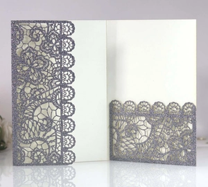 Macro shot of silver laser-cut lace invitation with glitter finish and floral details