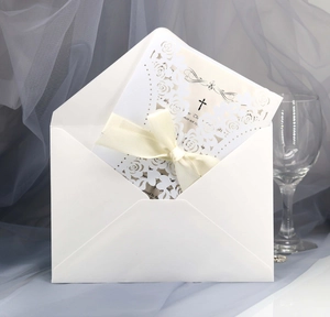 Detailed view of white laser-cut floral wedding invitation with elegant beige silk ribbon