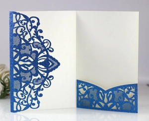 Detailed laser-cut wedding invitation featuring blue glitter floral patterns and ivory insert