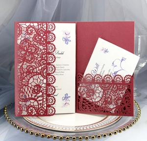 Macro detail of laser-cut floral pattern on burgundy wedding invitation cards