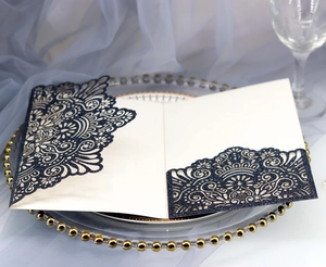 Detail of laser-cut mandala navy glitter invitation with cream insert on glass tray