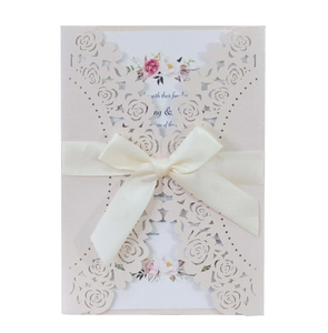Detail of laser-cut rose card with cream ribbon and floral wedding invitation insert